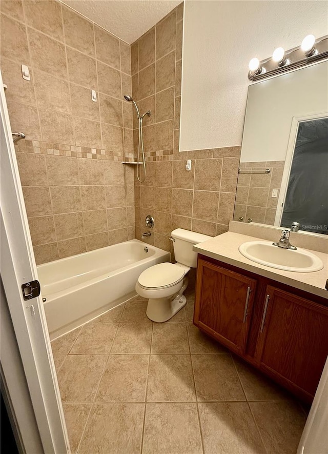 bathroom with shower / bathtub combination, tile walls, toilet, vanity, and tile patterned floors