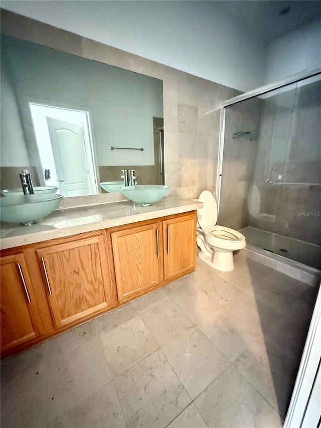 bathroom with a stall shower, toilet, and double vanity