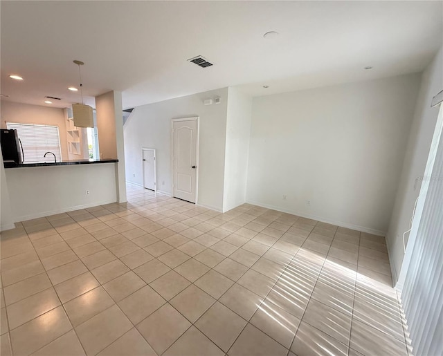 unfurnished living room with light tile patterned floors, recessed lighting, a sink, and baseboards