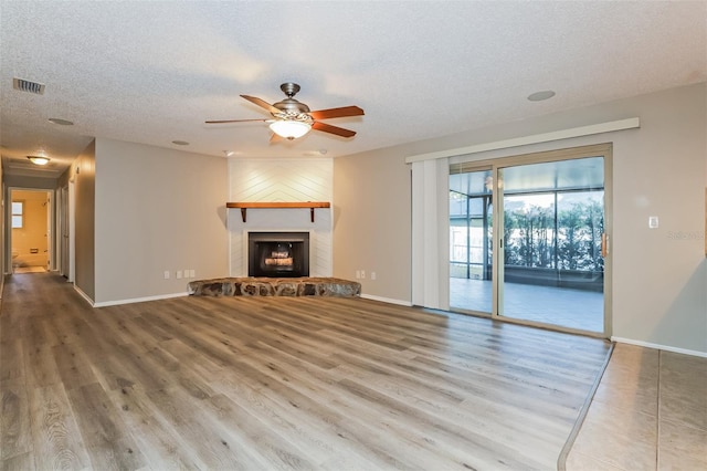2006 Sycamore Ln, Plant City, FL 33563 - unfurnished living room with a textured ceiling, a ceiling fan, wood finished floors, baseboards, and a large fireplace