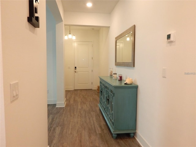 hall with dark wood-type flooring and baseboards