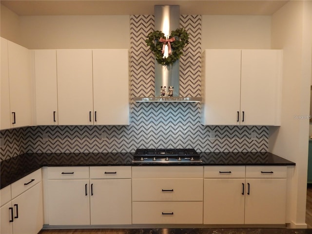 kitchen with stainless steel gas stovetop, dark countertops, backsplash, and white cabinetry