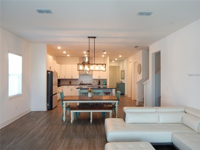 living area with dark wood finished floors, baseboards, a chandelier, recessed lighting, and stairs
