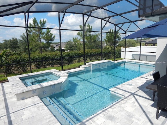 view of pool featuring a pool with connected hot tub, a patio area, and a lanai