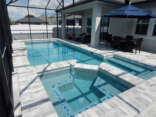 view of pool with a patio, a pool with connected hot tub, outdoor lounge area, and a lanai