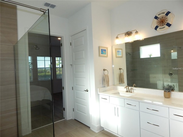 bathroom featuring tile patterned flooring, a tile shower, and vanity