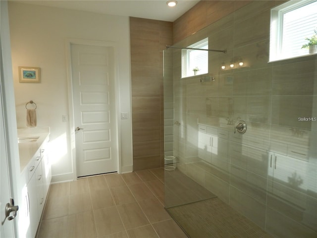 bathroom with a walk in shower, tile patterned flooring, vanity, and baseboards