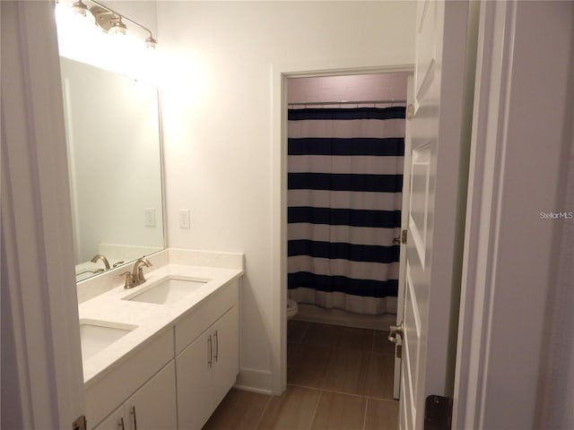 full bath with double vanity, toilet, and curtained shower