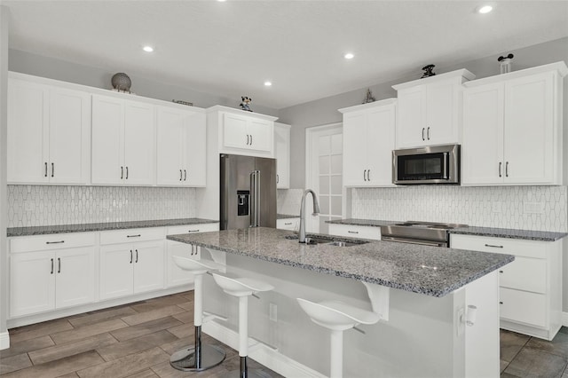 15975 Marina Bay Dr, Winter Garden, FL 34787 - kitchen with appliances with stainless steel finishes, a kitchen island with sink, tasteful backsplash, recessed lighting, and white cabinets