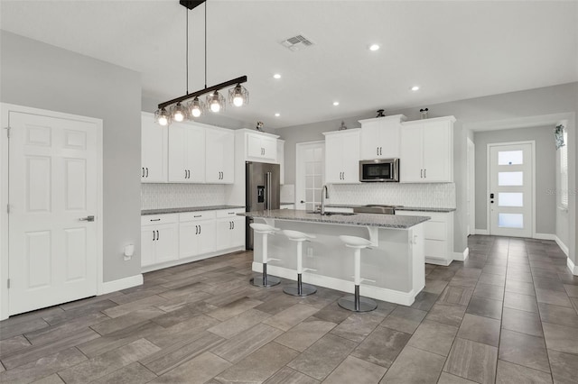 15975 Marina Bay Dr, Winter Garden, FL 34787 - kitchen featuring stainless steel appliances, a sink, backsplash, a center island with sink, and recessed lighting