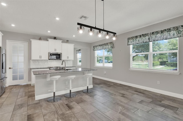 15975 Marina Bay Dr, Winter Garden, FL 34787 - kitchen with stainless steel appliances, light stone countertops, a center island with sink, a sink, and tasteful backsplash