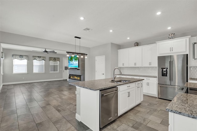 15975 Marina Bay Dr, Winter Garden, FL 34787 - kitchen featuring appliances with stainless steel finishes, a sink, recessed lighting, backsplash, and a glass covered fireplace