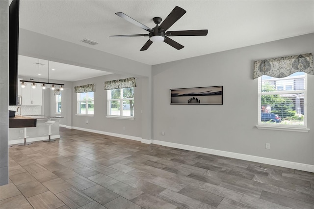 15975 Marina Bay Dr, Winter Garden, FL 34787 - unfurnished living room featuring ceiling fan, baseboards, and a sink