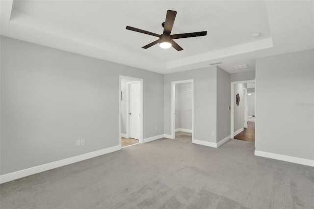 15975 Marina Bay Dr, Winter Garden, FL 34787 - unfurnished bedroom with a tray ceiling, carpet floors, baseboards, a walk in closet, and a ceiling fan