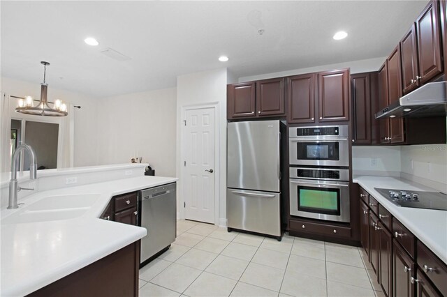 6941 Piazza St, Orlando, FL 32819 - kitchen with appliances with stainless steel finishes, a sink, under cabinet range hood, light countertops, and a chandelier