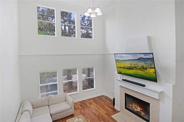 6941 Piazza St, Orlando, FL 32819 - unfurnished living room featuring wood finished floors, a tile fireplace, baseboards, and a chandelier