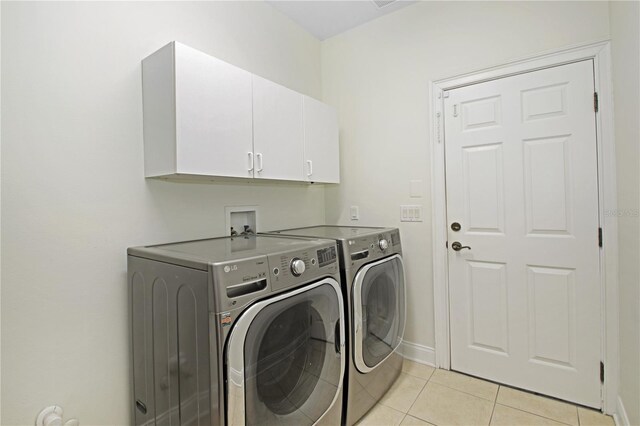 6941 Piazza St, Orlando, FL 32819 - laundry area with cabinet space, washer and clothes dryer, light tile patterned flooring, and baseboards