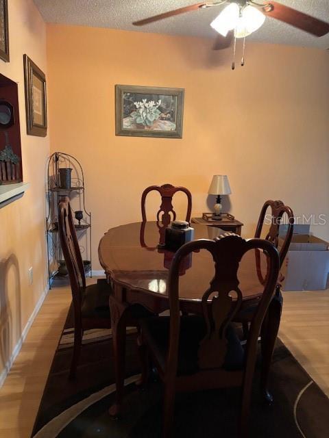 25306 Northlake Dr Unit 25306, Sanford, FL 32773 - dining area featuring ceiling fan, wood finished floors, a textured ceiling, and baseboards