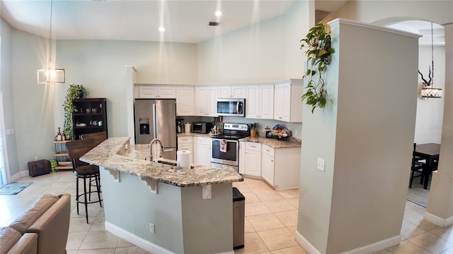 2343 Walnut Heights Rd, Apopka, FL 32703 - kitchen with stainless steel appliances, a kitchen bar, light tile patterned flooring, light stone countertops, and high vaulted ceiling
