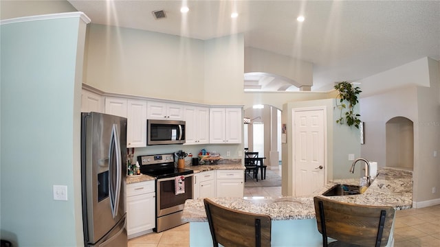 2343 Walnut Heights Rd, Apopka, FL 32703 - kitchen featuring stainless steel appliances, arched walkways, light tile patterned floors, a sink, and a towering ceiling