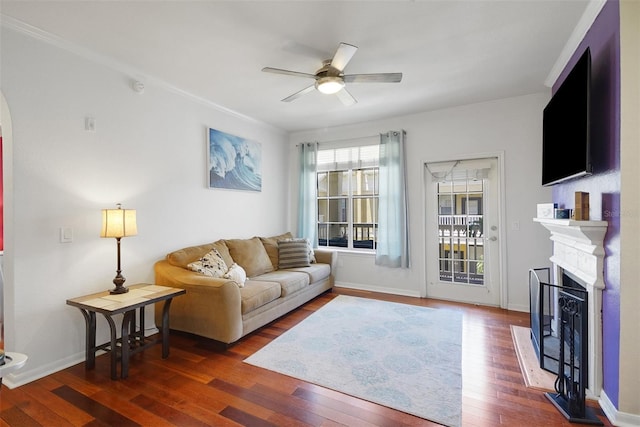living area featuring ceiling fan, a fireplace, wood finished floors, and arched walkways