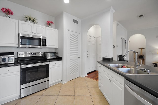 kitchen with stainless steel appliances, a sink, dark countertops, crown molding, and recessed lighting