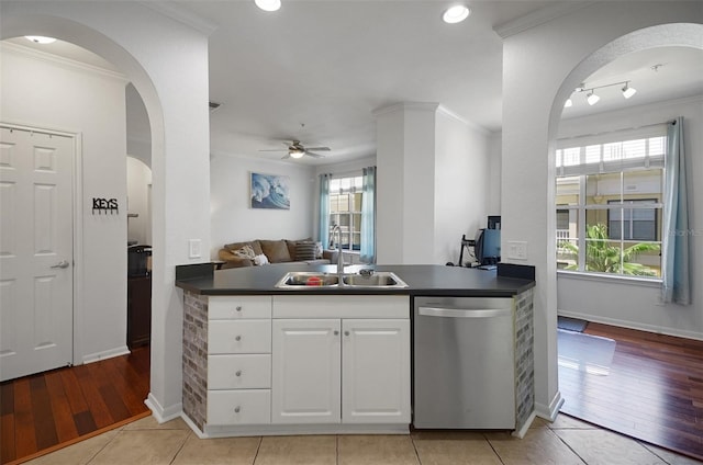 kitchen with dishwasher, a sink, dark countertops, arched walkways, and crown molding