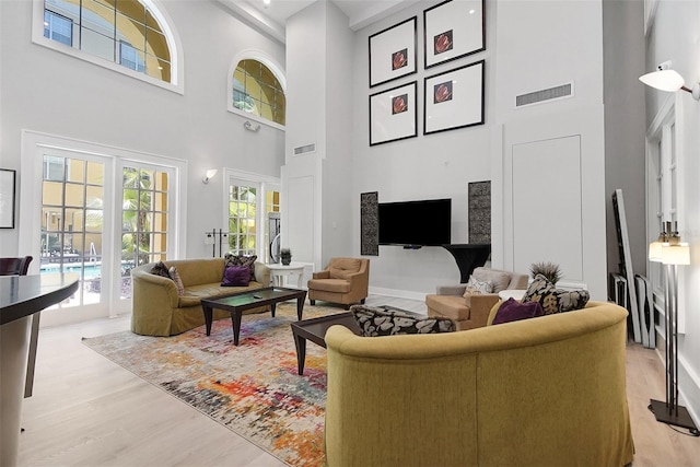 living area featuring a high ceiling, light wood-style flooring, and baseboards