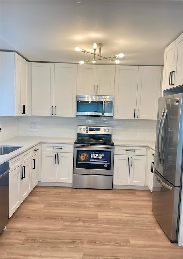 331 N Dollins Ave, Orlando, FL 32805 - kitchen featuring stainless steel appliances, white cabinets, decorative backsplash, light countertops, and light wood-style floors