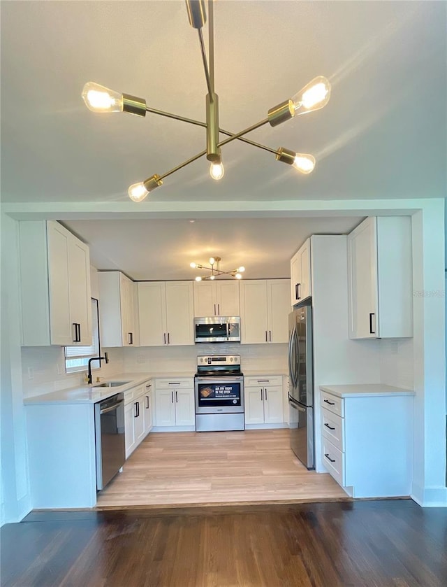 331 N Dollins Ave, Orlando, FL 32805 - kitchen featuring appliances with stainless steel finishes, white cabinetry, light countertops, and light wood finished floors