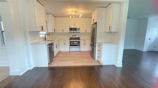 331 N Dollins Ave, Orlando, FL 32805 - kitchen featuring appliances with stainless steel finishes, light wood-type flooring, light countertops, decorative backsplash, and a chandelier