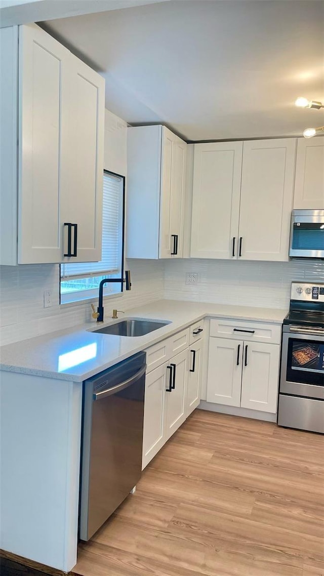 331 N Dollins Ave, Orlando, FL 32805 - kitchen with appliances with stainless steel finishes, light countertops, white cabinetry, decorative backsplash, and light wood-style flooring