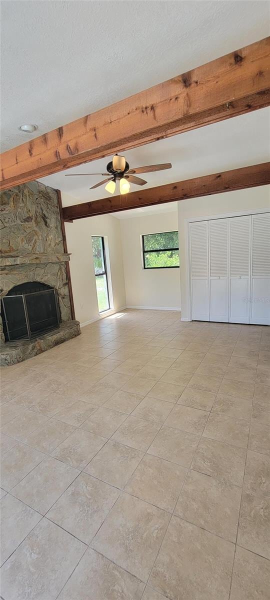 122 N Cedarview Ter, Inverness, FL 34453 - unfurnished living room with beam ceiling, a fireplace, light tile patterned floors, ceiling fan, and a textured ceiling