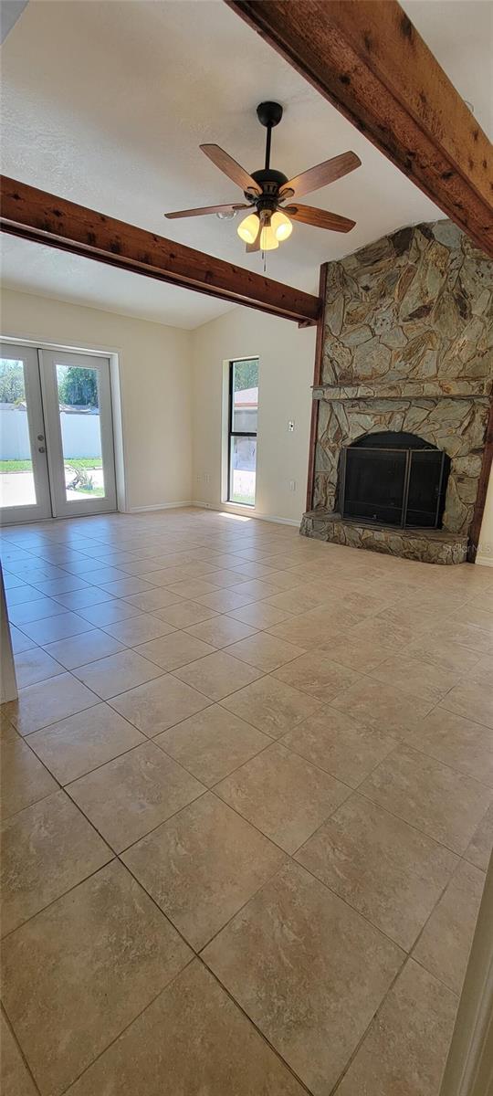 122 N Cedarview Ter, Inverness, FL 34453 - unfurnished living room featuring beamed ceiling, tile patterned floors, a fireplace, and a ceiling fan