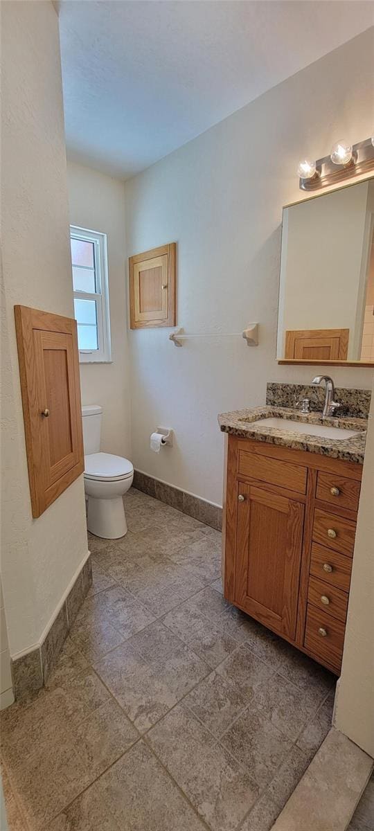 122 N Cedarview Ter, Inverness, FL 34453 - bathroom featuring baseboards, vanity, toilet, and stone finish floors