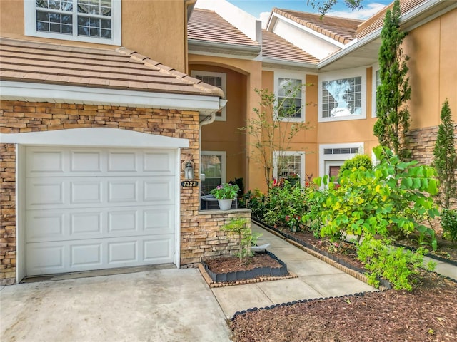 7323 Cypress Grove Rd Unit 87, Orlando, FL 32819 - view of exterior entry with stucco siding, concrete driveway, and a garage