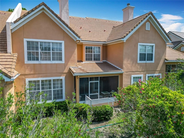 7323 Cypress Grove Rd Unit 87, Orlando, FL 32819 - rear view of house with a chimney, stucco siding, a sunroom, and a tile roof