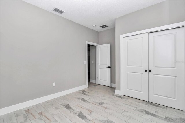6805 SW 131st Cir, Ocala, FL 34481 - unfurnished bedroom with light wood-style floors, a closet, baseboards, and a textured ceiling