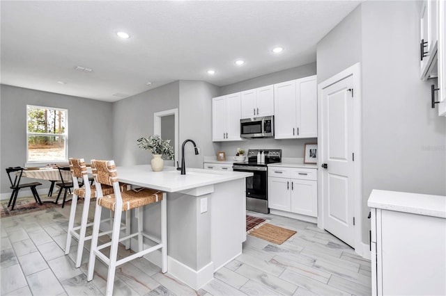 6805 SW 131st Cir, Ocala, FL 34481 - kitchen with stainless steel appliances, a sink, recessed lighting, white cabinets, and a breakfast bar area