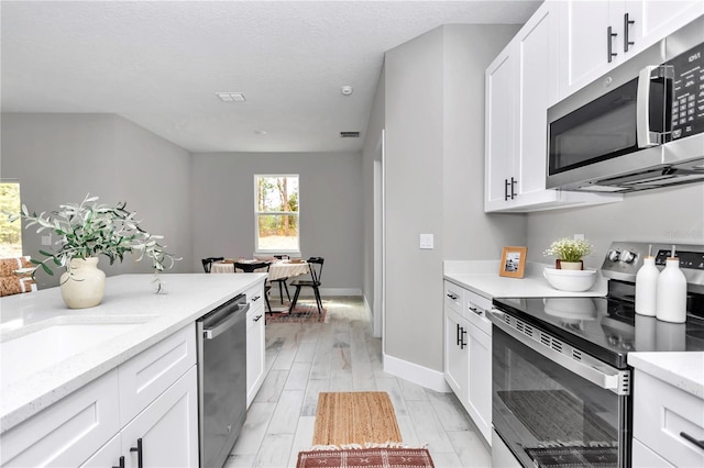 6805 SW 131st Cir, Ocala, FL 34481 - kitchen featuring stainless steel appliances, white cabinets, light stone countertops, and baseboards