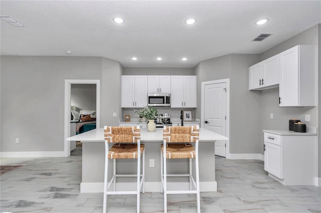 6805 SW 131st Cir, Ocala, FL 34481 - kitchen featuring stainless steel microwave, a center island, light countertops, white cabinetry, and recessed lighting