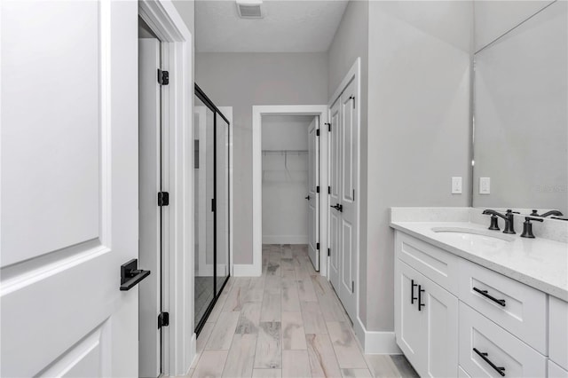 6805 SW 131st Cir, Ocala, FL 34481 - full bathroom featuring a stall shower, vanity, a spacious closet, baseboards, and wood finished floors