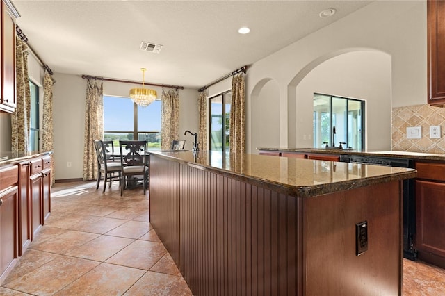 3041 Boating Blvd, Kissimmee, FL 34746 - kitchen featuring an island with sink, tasteful backsplash, a chandelier, dark stone countertops, and light tile patterned floors