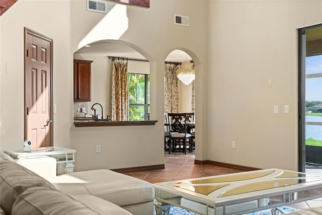 3041 Boating Blvd, Kissimmee, FL 34746 - living area with arched walkways, baseboards, light tile patterned flooring, a high ceiling, and a chandelier