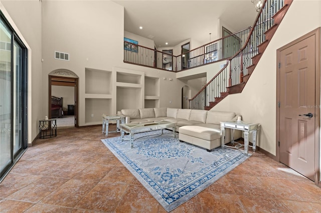 3041 Boating Blvd, Kissimmee, FL 34746 - living room featuring a towering ceiling, built in features, stairway, arched walkways, and baseboards