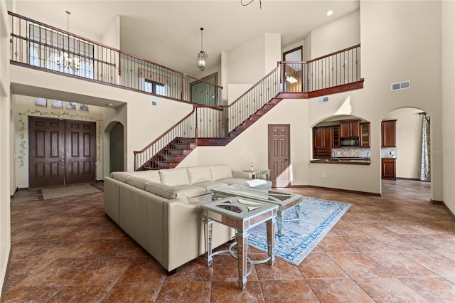 3041 Boating Blvd, Kissimmee, FL 34746 - living room with a towering ceiling, arched walkways, stairway, baseboards, and a chandelier