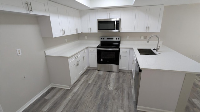 609 Whittingham Pl, Lake Mary, FL 32746 - kitchen with appliances with stainless steel finishes, a sink, a peninsula, light wood-type flooring, and white cabinetry