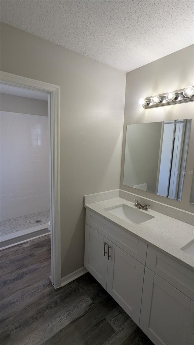 609 Whittingham Pl, Lake Mary, FL 32746 - bathroom featuring wood finished floors, double vanity, a textured ceiling, toilet, and a shower