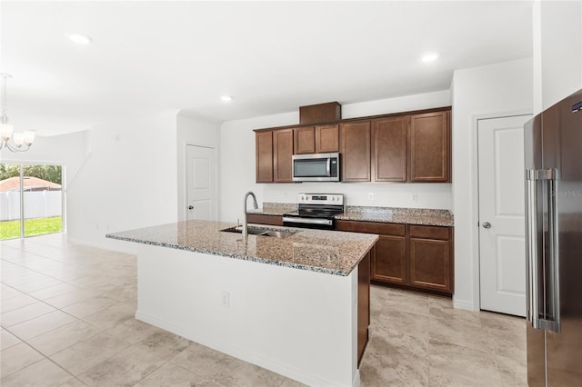 1396 Mirabella Cir, Davenport, FL 33897 - kitchen with stainless steel appliances, a sink, light stone counters, a chandelier, and a kitchen island with sink