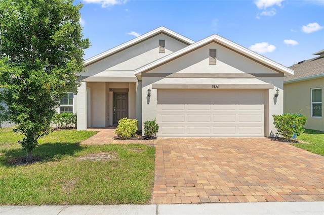 9356 St Therese St, Groveland, FL 34736 - view of front of property with stucco siding, an attached garage, decorative driveway, and a front lawn